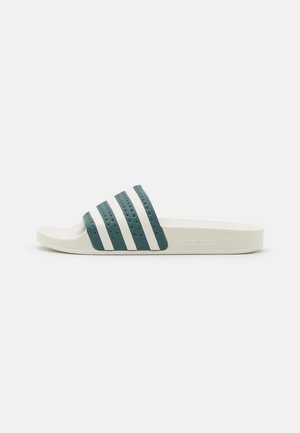 Biała klapka z ciemnozielonym i białym paskiem w paski o fakturowanej powierzchni, otwarty nosek i wytłoczone logo Adidas z boku podeszwy.