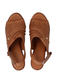 Braune Leder-Sandalen mit durchbrochenem Design, offener Zehenpartie, Knöchelriemen und dekorativem Knopfdetail. Glatte Textur mit leicht glänzendem Finish.