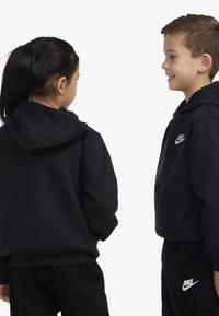 Juodi medvilnės mišinio gobtuvu megzti džemperiai su priekinių kišenių ir siuvinėtais baltais Nike logotipais ant krūtinės ir kelnių.