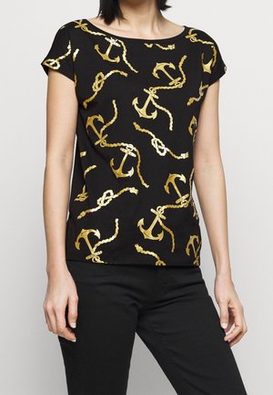 Zwart shirt met korte mouwen met patroon van gouden ankers en gedraaide touwen, gedragen met een zwarte broek.