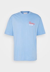 Ljust blå bomull T-shirt med korta ärmar, rund halsringning och en tryckt design med texten "on vacation CLUB" i kontrasterande färger.