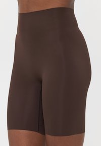 Bruine high-waisted shaping shorts van soepel, rekbaar materiaal. Beschikken over een naadloos ontwerp met een lengte tot halverwege de dijen.