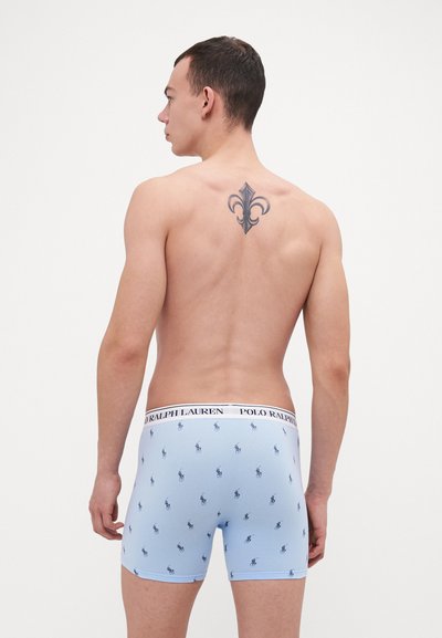 Svetlo modri bokserice z ponavljajočim se temnim vzorcem malih polo igralcev, s belim pasom, na katerem je napis "POLO RALPH LAUREN."