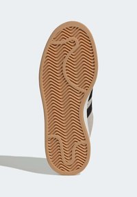 Gummiaußensohle mit wellenartiger Textur und zentralem Rillenmuster. Die Farbe ist hellbraun mit einem kontrastierenden schwarzen Obermaterial.