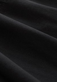 Zwarte stof met een gladde textuur, met subtiele ribbels en plooien, die het licht absorbeert en diepte in kleur toont.