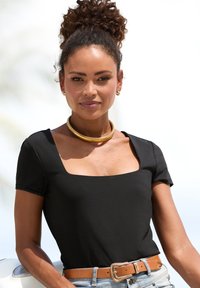 Mustad lühikeste varrukatega bodi, millel on ruudukujuline kaelus, koos heledate denim lühikesed pükste ja pruuni vööga, millel on kuldne tõlv. Kuldsed choker-kette.