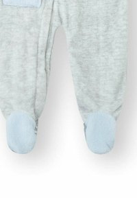 Pijama suave de bebé en gris claro con suelas en azul claro, puños elásticos en los tobillos y pies adjuntos, visto desde las piernas hacia abajo.