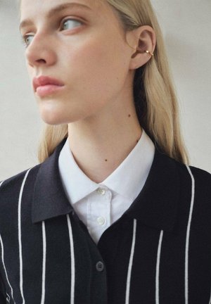 Black cardigan with white vertical stripes, featuring a white collared shirt underneath. Smooth texture, classic design, buttoned front.