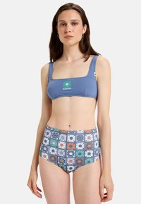 Top de bikini azul con escote cuadrado y parche de logo, acompañado de la parte de abajo de tiro alto con un patrón floral en varios colores.