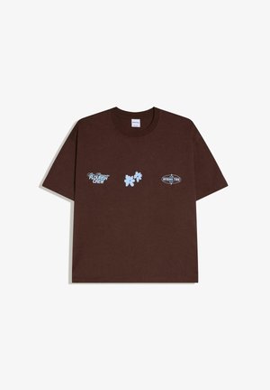 Brown short-sleeve crew neck t-shirt with blue "Flourish Crew," leaf graphic, and "Spring Tide 2020" text on the chest.