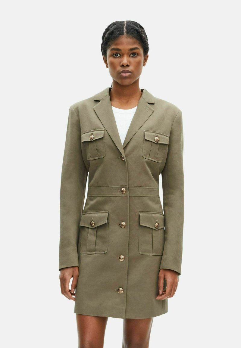 Olivgrünes Blazer-Kleid aus glattem Stoff, das zwei Brusttaschen, zwei Fronttaschen und große goldene Knopf-Akzente aufweist.