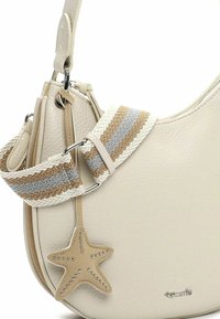Sac à main en cuir texturé beige avec bandoulière en tissu rayé, breloque en cuir en forme d'étoile avec clous métalliques et logo de la marque en métal argenté.