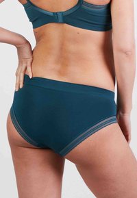 Türkisfarbene nahtlose Unterhose aus glattem Material mit einem breiten Bund und subtiler Spitzenborte an den Beinöffnungen. Keine sichtbaren Beschläge.