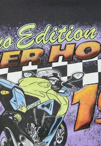 Camiseta negra con un gráfico colorido de una motocicleta, con el texto "Super Hot" y un patrón a cuadros en tonos amarillos, púrpuras y naranjas.