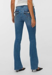 Razširjene modre kavbojke iz denima s srednjim pasom, ki imajo dvojne zadnje žepke okrašene z vezenimi detajli in gladko teksturo.