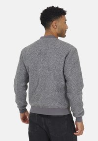 Maglione grigio a trama con colletto e polsini a coste, caratterizzato da un design semplice e classico e un materiale spesso e caldo.