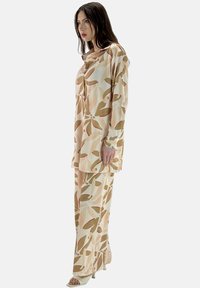 Maglia a maniche lunghe e pantaloni coordinati in tessuto leggero con motivi di foglie beige e verdi. Vestibilità ampia con scollo a girocollo.