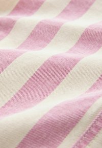 Gros plan sur un tissu à rayures diagonales roses et blanches, montrant un tissage texturé et de légers plis.