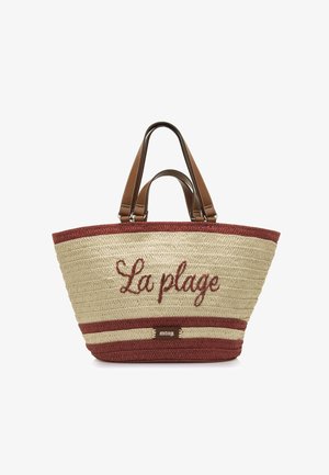 Bolso de paja tejido con ribete rojo, asas de cuero marrón y "La plage" bordado en rojo en el frente.
