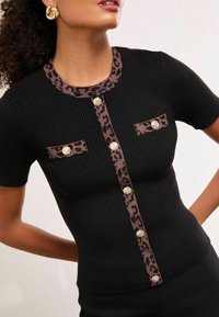 Mustat ribbimerkit lyhyet hihat -paita, jossa on leopardikuosiset kaulus ja taskutehosteet, viimeistelty hopeasävyisillä napeilla.