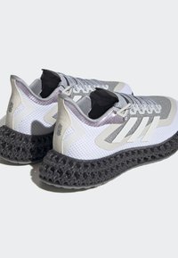 Scarpe da ginnastica bianche e grigie con una tomaia in rete, una intersuola testurizzata e una suola nera distintiva con un motivo a reticolo.