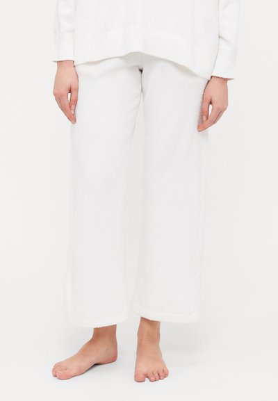 White wide-leg lounge pants made of soft, textured fabric. Features a simple hem and a relaxed fit, paired with a loose-fitting white top.