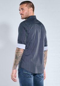 Kurzärmeliges Hemd mit dunklem geometrischem Muster, ausgestattet mit Stehkragen, hellfarbigen Manschetten und glatter Textur.