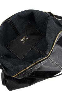 Black leather handbag with a soft suede interior, gold zipper, and a textured leather label showing brand name. No external embellishments.