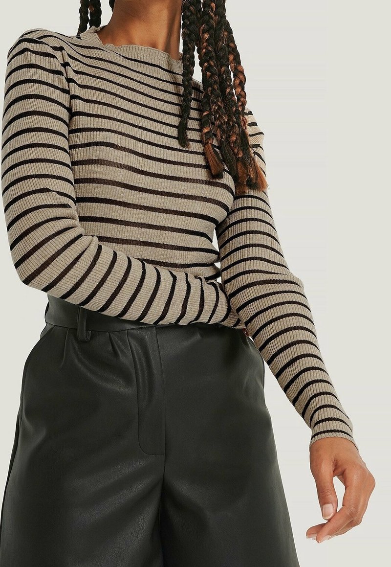 Ruskea ja beige raidallinen ribattutakki pitkillä hihoilla, jossa on pyöreä kaula-aukko, yhdistettynä korkeavyötäröisiin mustiin nahkahousuihin.