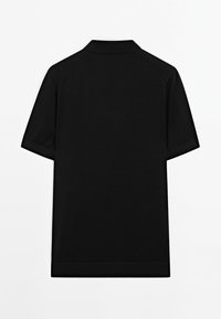 Černé polo tričko s krátkým rukávem s klasickým límcem, měkkou texturou a čistým, jednoduchým designem bez viditelných log nebo vzorů.