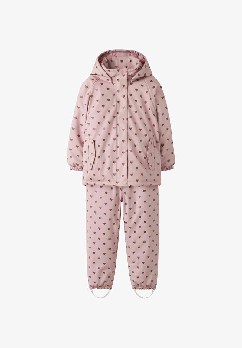 Combinaison de pluie enfant deux pièces rose imperméable avec capuche et motif de petits cœurs marron sur l’ensemble, poignets élastiqués et sangles aux pieds du pantalon.