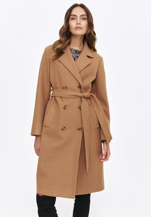 Beiger Wollmischmantel mit doppelt geknöpftem Design, taillierter Taille, seitlichen Taschen und Reverskragen. Glatte Textur und maßgeschneiderte Passform.