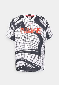 Koszulka Nike z krótkim rękawem w czarno-białą siateczkę, z wyraźnym czerwonym logo Nike na piersi. Okrągły dekolt.