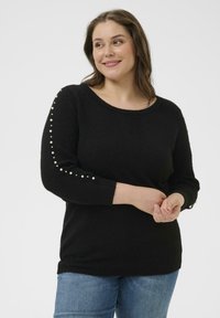 Schwarzer Strickpullover mit rundem Ausschnitt, langen Ärmeln und perlenähnlichen Akzenten entlang des linken Arms, weiche Textur.