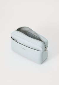 Borsa sintetica blu chiaro con zip, caratterizzata da un motivo testurizzato sul davanti, finitura liscia sulla parte superiore e un tirante in metallo di tonalità argentata.