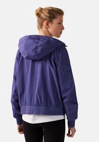 Paarse lichte jas met een capuchon, elastische manchetten en tailleband. Glad oppervlak en minimalistisch ontwerp, geschikt voor casual draag.