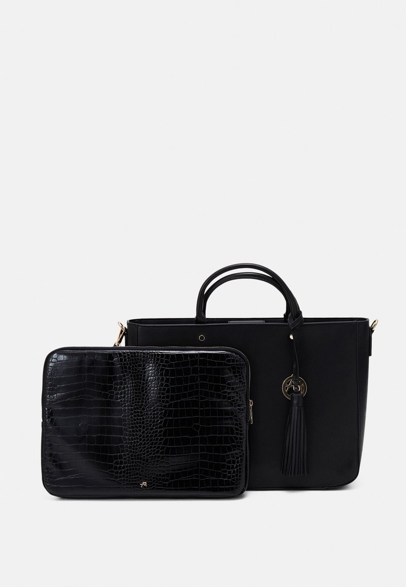 Sac cabas en cuir noir avec doubles anses et détail pompon à côté d'une pochette noire texturée zippée avec motif crocodile.