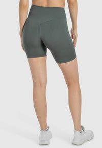 Pantalones cortos deportivos de tiro alto en un verde oscuro, hechos de un material suave y elástico, con un diseño ajustado y costuras planas para mayor comodidad.