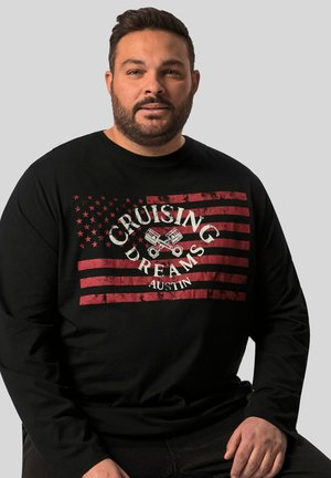 Sort langærmet t-shirt med et slidt rød-hvidt grafik af stjerner og striber med teksten "CRUISING DREAMS AUSTIN" i midten.