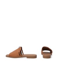 Tan leather slide sandals with open toe, minimal design, flat soles, and decorative accents at the front strap.