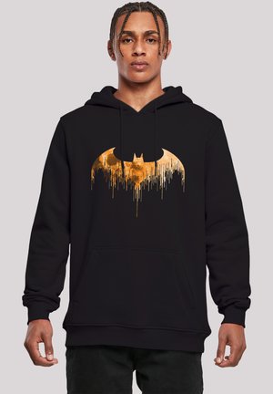 Sort hættetrøje med et stort, dryppende guld Batman-logo. Lavet af blødt materiale, med en frontlomme og snøre i hætten.