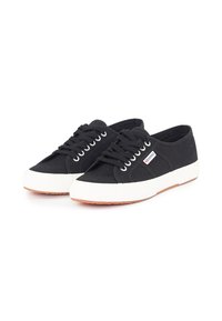 Sorte kanvas sneakers med en hvit gummisåle, rund tå og seks snorelaterte hull. Har en logotagg på siden og et teksturert mønster.