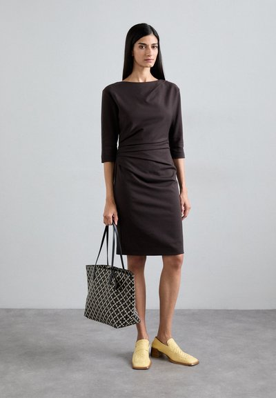 Form-fitting brown dress with three-quarter sleeves, textured fabric, and a gathered waist. Accessories include a black and white patterned tote and yellow heeled shoes.