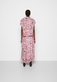Conjunto floral de dos piezas que incluye una blusa de manga corta y una falda larga en rosa con acentos en negro y crema, confeccionado en un tejido ligero.