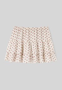 Jupe blanche à volants avec un petit imprimé floral rouge. Dotée d'une taille élastique et d'un ourlet en dentelle. Tissu léger au toucher doux.