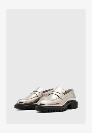 Metalni srebrni loafers s niskom blok petom i teksturiranom gumenom potplatom. Imaju horizontalnu traku preko gornje strane i detalje šivanja.