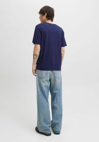 Mørkeblå t-shirt med en afslappet pasform, kombineret med lyseblå vide jeans. Sættet har minimal detaljering og et afslappet design.
