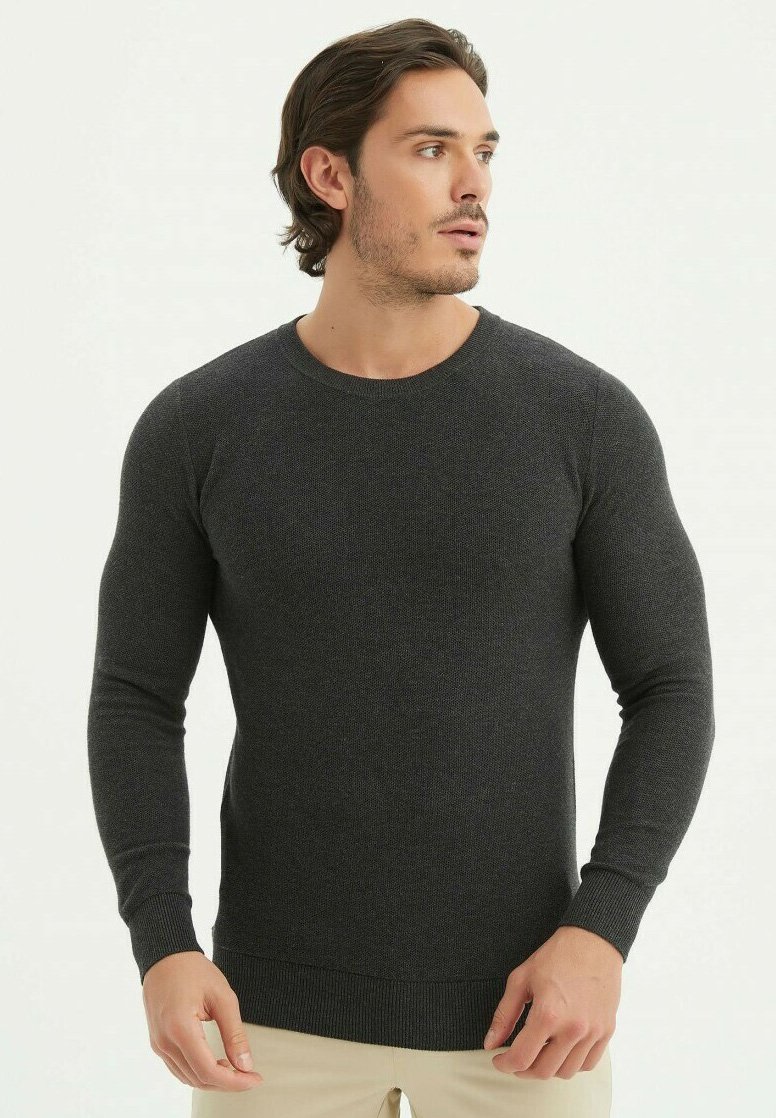 Pull gris foncé en tricot doux avec un col rond, des manches longues et des bords côtelés au niveau des poignets et de l'ourlet. Design simple et ajusté.
