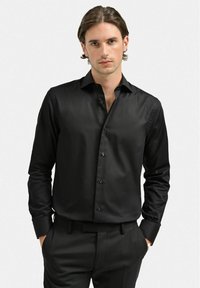 Svart långärmad skjorta, slät tyg, knäppning fram, slim fit, en enda ficka, kontrasterande svarta knappar, klassisk krage.