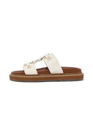 Witte leren slipper sandaal met goudkleurige kettingdetail, bruine gelaagde zool en contrasterend stiksel langs de rand. Vlak ontwerp voor gemakkelijk dragen.